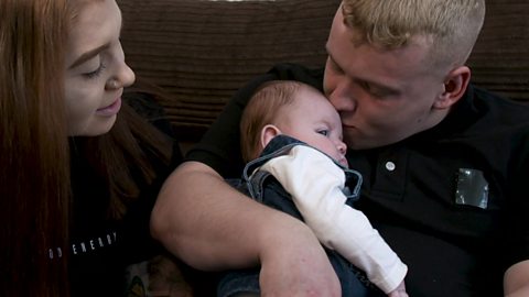 A mum talking to her daughter while dad kisses the baby on the head.