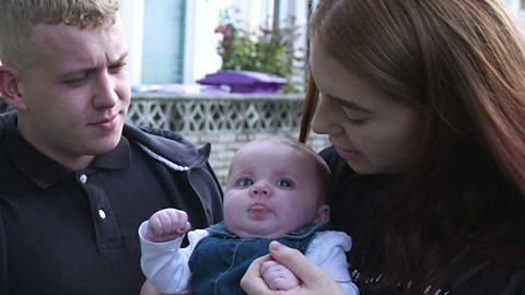 A mum and dad talking to their baby daughter.