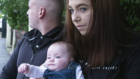 Parents looking at cars with their baby.