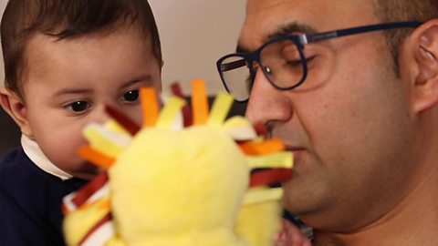 A dad talking to his son about a lion glove puppet.