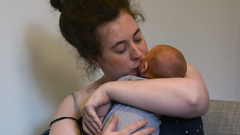 A mum cuddling and kissing her newborn son.