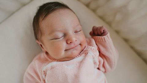 Baby in a pink jumper sleeping