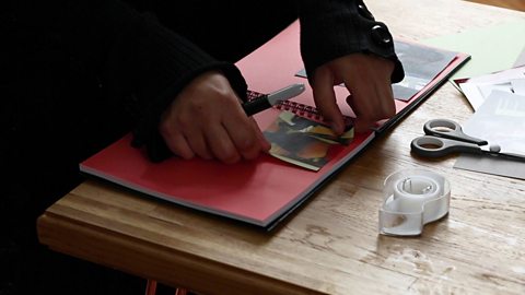 Hands sticking a photo of a mum's pregnancy bump in a scrapbook.