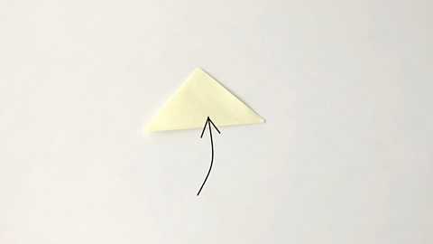 The square of paper is now folded in half to make a triangle.