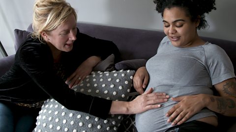 A woman with feeling her pregnant daughter's belly.