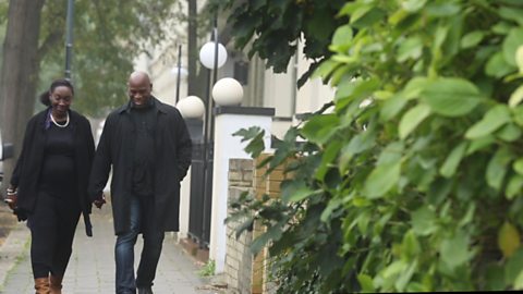 Pregnant woman walking with her partner holding hands.