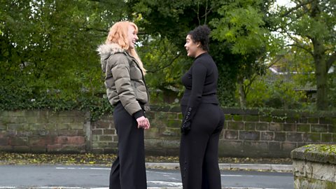 Pregnant woman talking to her friend outdoors.