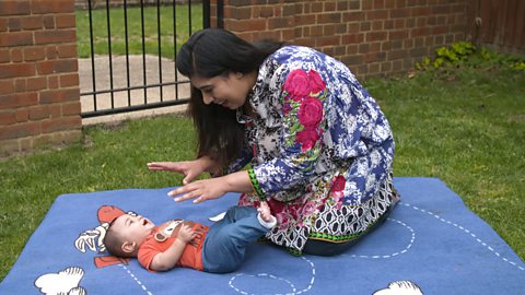 A mum playing with their baby son on a soft mat.