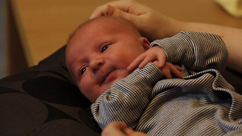 A baby looking disinterested on mum's lap.