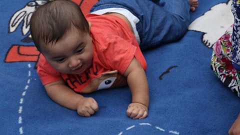 A baby boy lifting his head while on his tummy.