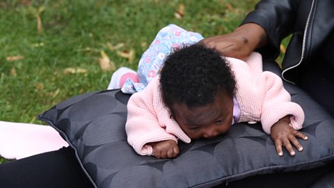 A baby girl struggling to keep their head raised while on her tummy.