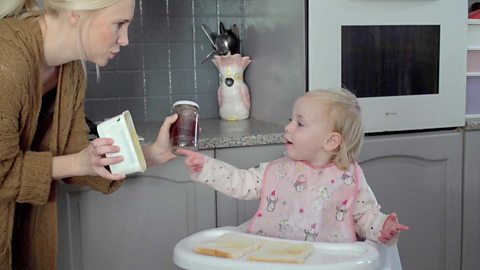 A little girl pointing and telling her mum she wants butter for her toast.