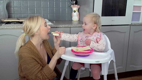 A little girl offering her mum a bite of her toast.