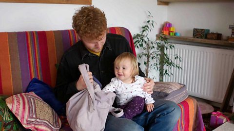 A young man and his little sister holding a pillowcase.