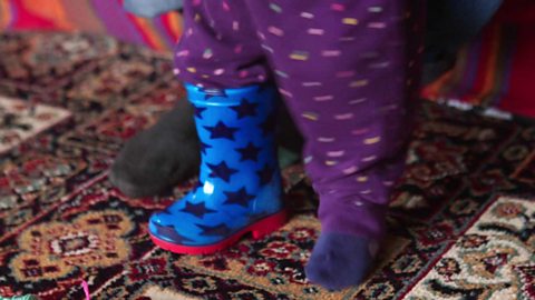 A little girl with a welly on one foot.