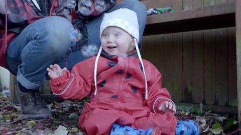 A little girl laughing at some bubbles.