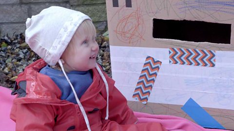 A little girl smiling next to a homemade postbox.