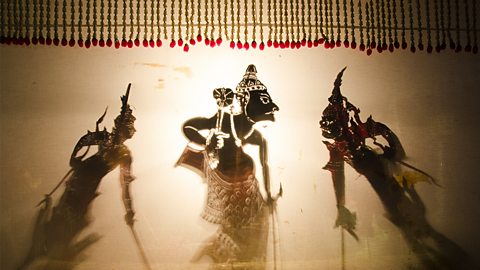 Three sharp shadow puppet characters are shown against a white screen, which has been brightly lit from behind.