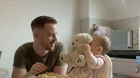 A little girl hiding her face behind a teddy.