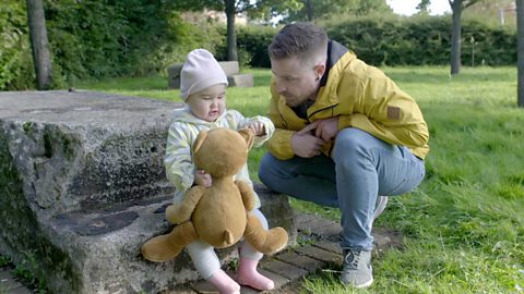 A little girl showing her dad the ear of her teddy.