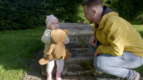 A dad singing to his daughter in the park.