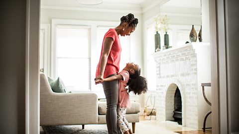 A mother looks down at her daughter who stands on her feet