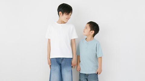 Two brothers stand side by side comparing their height