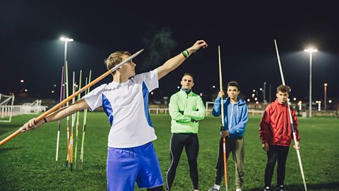 A group of boys and their coach practise throwing javelins