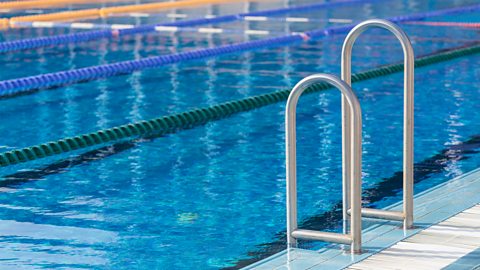 A photo of a swimming pool. There is a small ladder and lanes.