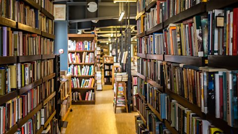 A photo of the inside of a library. There are lots of books on tall shelves.