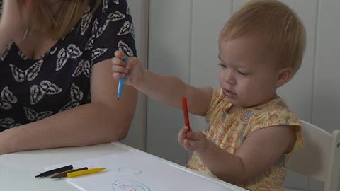 Little girl holding a blue and red felt tip pen. 