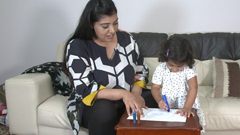 Mum and daughter drawing faces on a piece of paper. 