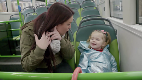 Mum and little daughter on bus, mum pointing to her ear