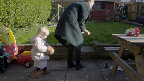 Woman and toddler on garden patio crouching down