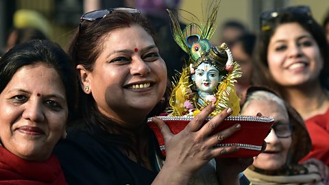 Hinduism – Hindu women with a murti of Lord Krishna