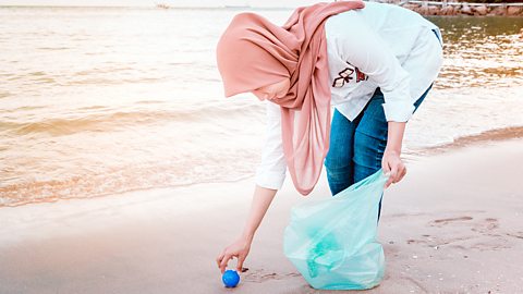 Islam – A Muslim woman cleaning a beach