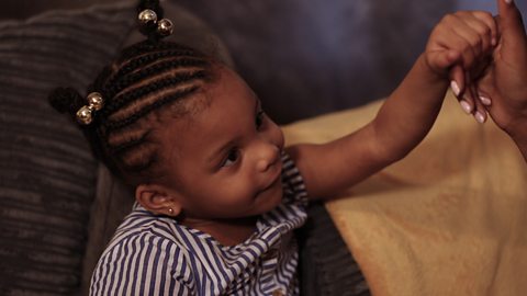 Little girl with braids holding mum's hand.