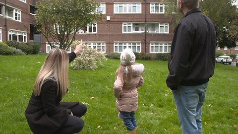 Backs of heads of mum, child, dad outside looking at a building. 