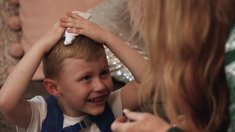 Little boy smiling as he puts a sock on his head.