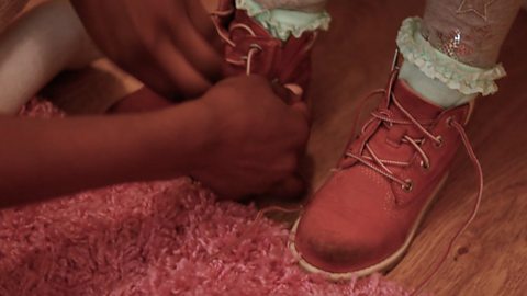 Little girl's shoelaces getting tied up by mum.