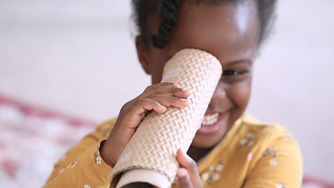 Little girl holding a cardboard tube to her eye. 