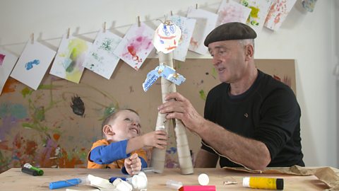 Little boy and granddad making scrap person out of cardboard tubes.