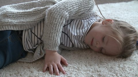 Little girl sleeping on a rug on the floor.