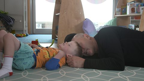 Little boy and granddad laying on the floor sleeping.