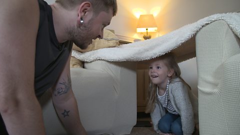 Little girl under a blanket den with her dad.