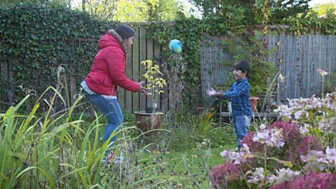 Mum and son throwing a ball in the garden. 