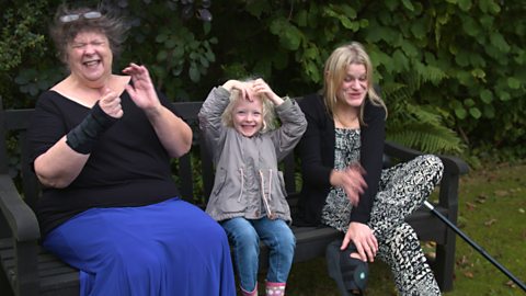 Grandma, child, mum sat on a bench outside.