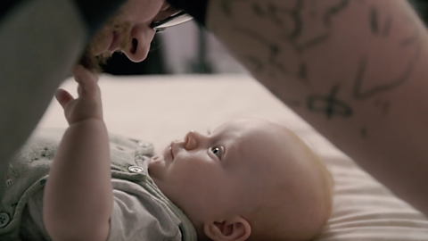 Baby reaching his arm to dad's face.