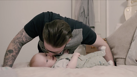 Dad kissing baby's face on the bed.