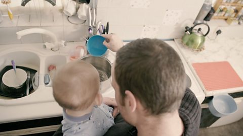 Backs of head of dad and baby over the sink.